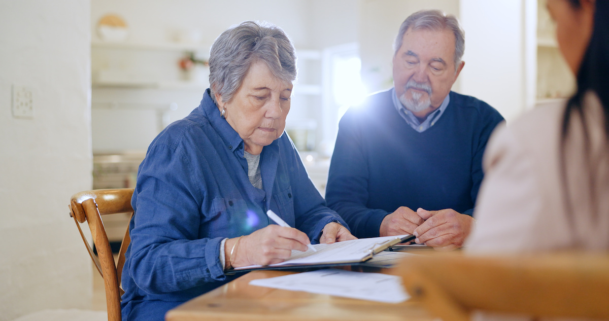Senior citizen couple signing a paper for relocation services, contact Downsize Allies